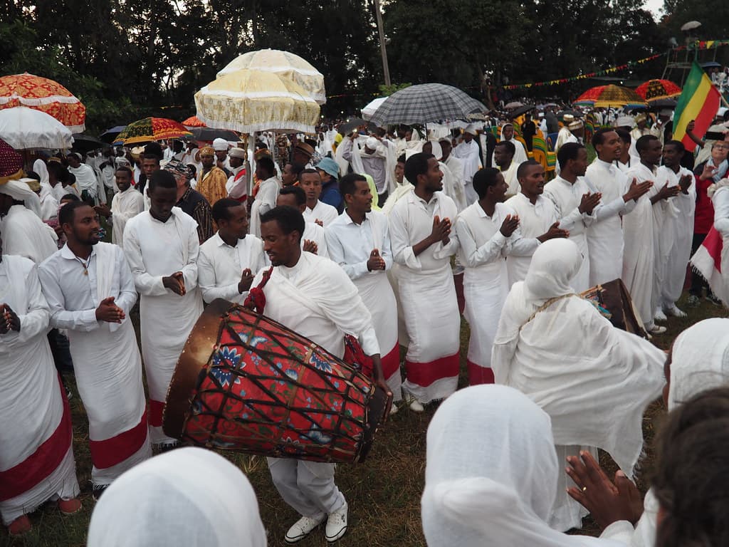A man beats a large drum among worshippers dressed in white at a Meskel celebration in Bahir Dar, Ethiopia