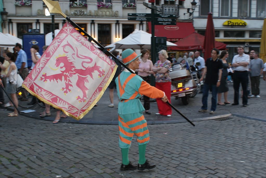 A flag-waver in costume throws a large banner with a red lion during the Ommegang procession in Brussels