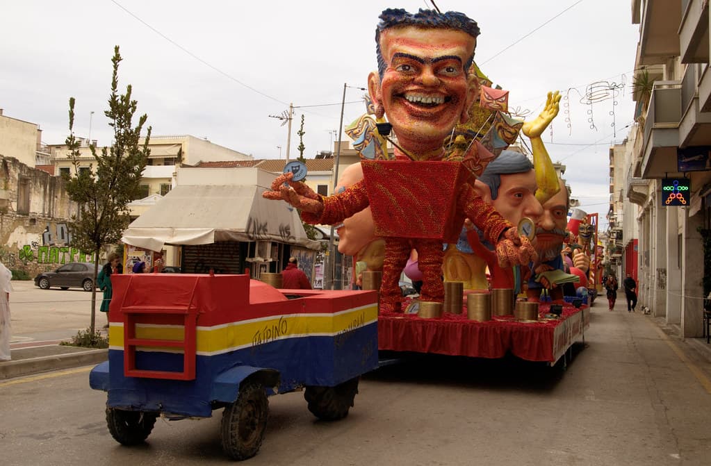 Giant papier-mâché floats with caricature heads line a street in Patras before the Grand Parade