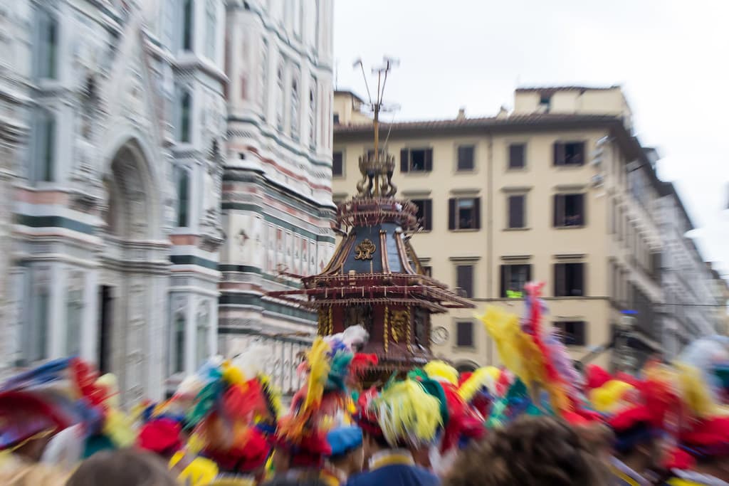 The tall antique Brindellone cart stands beside the marble facade of Florence cathedral as flag-wavers in coloured costumes gather