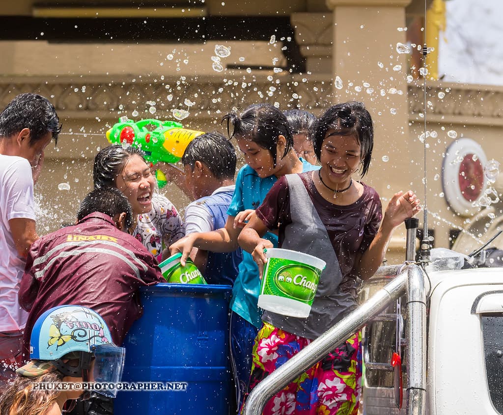 Smiling people soaking each other with buckets of water at Songkran