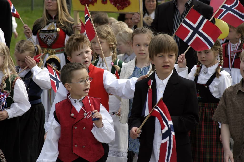 Boys in red bunad vests wave Norwegian flags in a children's parade in Førde on May 17