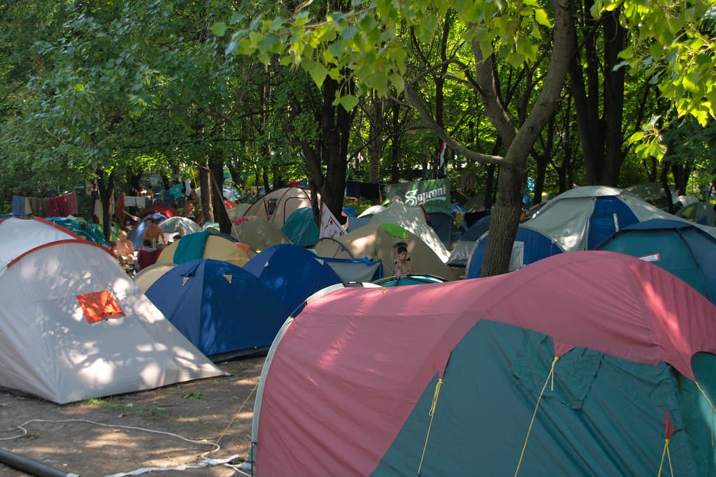 Colourful tents are pitched close together under shady trees at the Sziget Festival campsite on the island