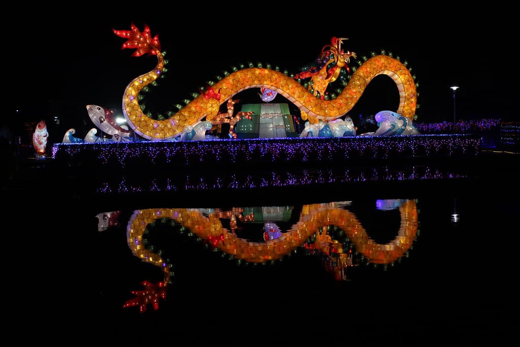 A glowing golden dragon lantern reflected in dark water at the 2017 Taiwan Lantern Festival in Yunlin