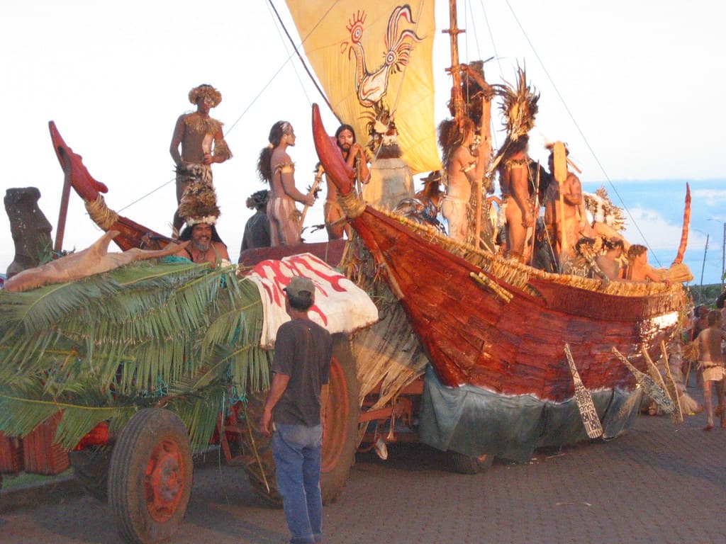 A float shaped like a reed boat with a painted sail, carrying people in traditional dress, in the Tapati parade on Rapa Nui