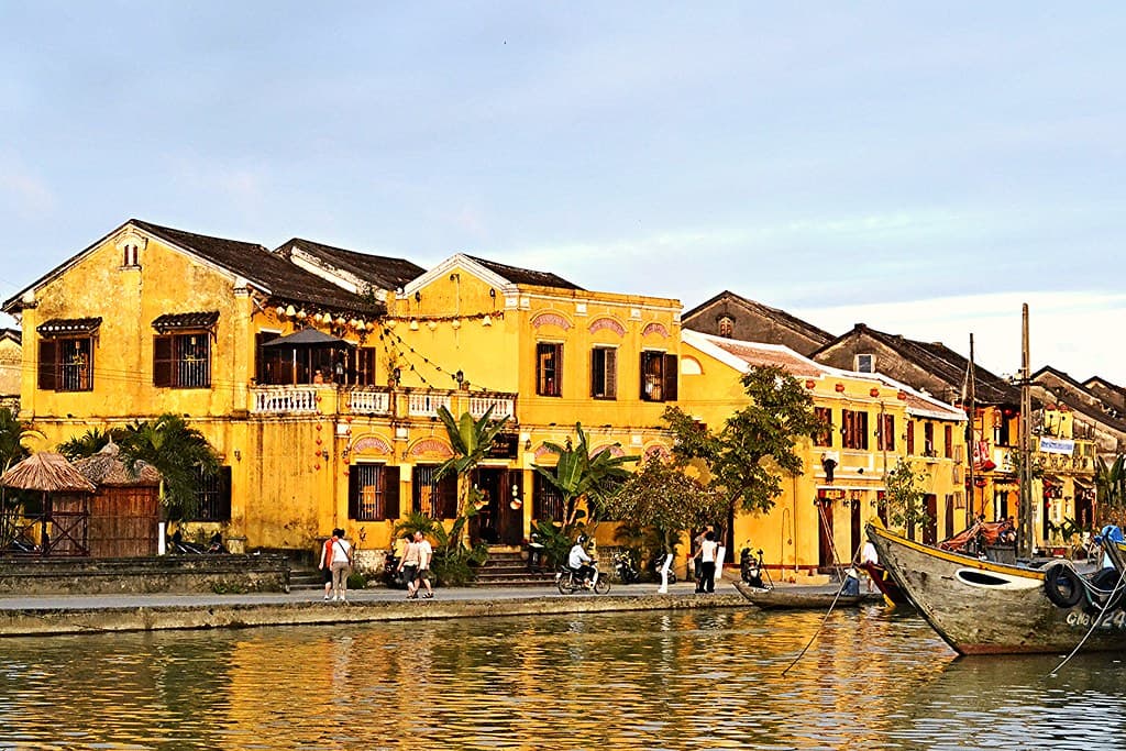 Yellow colonial-era buildings along the riverbank in Hoi An at dusk