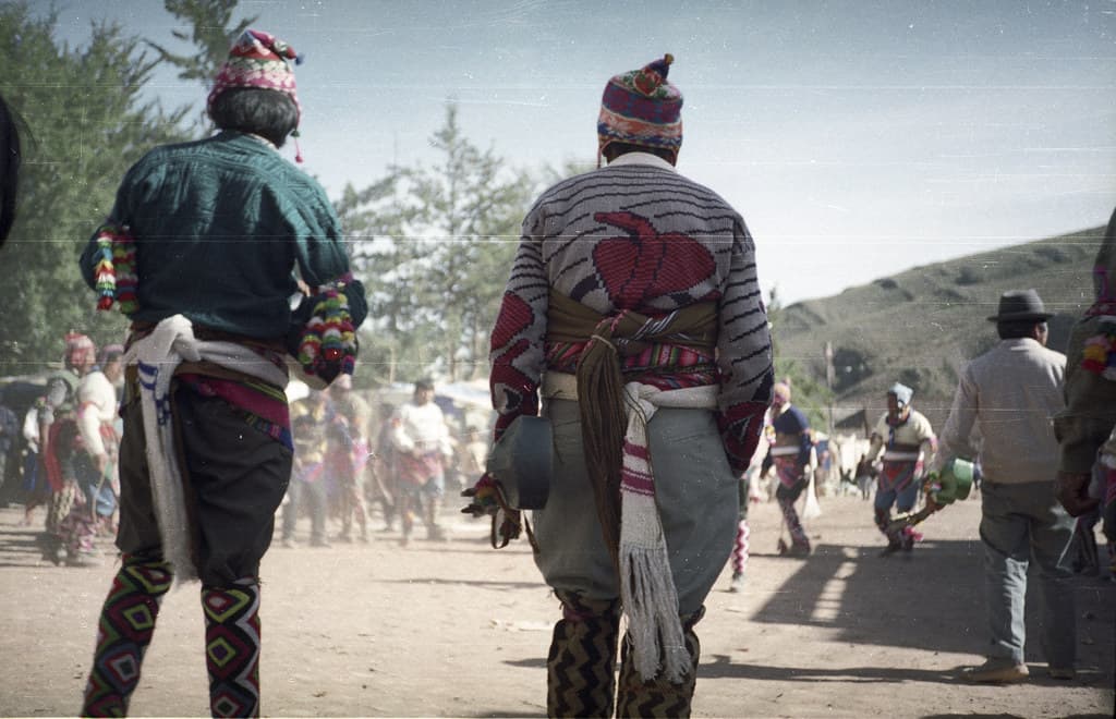 Men in traditional dress and helmets face each other in a plaza during the Tinku festival in Macha, Bolivia